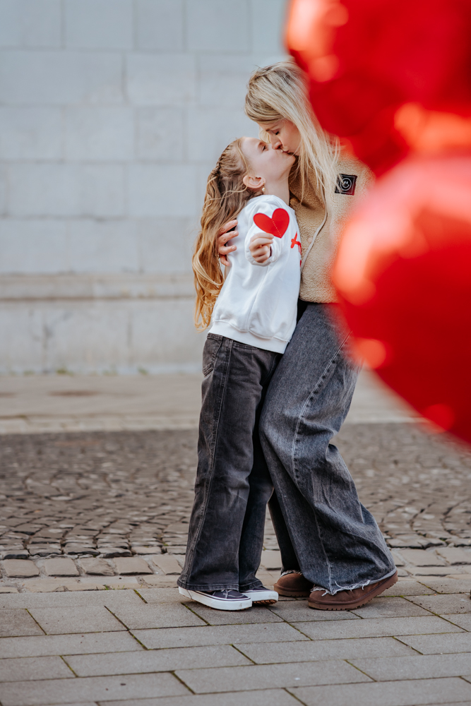 HOCHZEITSFOTOGRAFIN UND FAMILIENFOTOGRAFIN – MICHELLE 2 Tochter küsst Mutter versteckt hinter Herzen