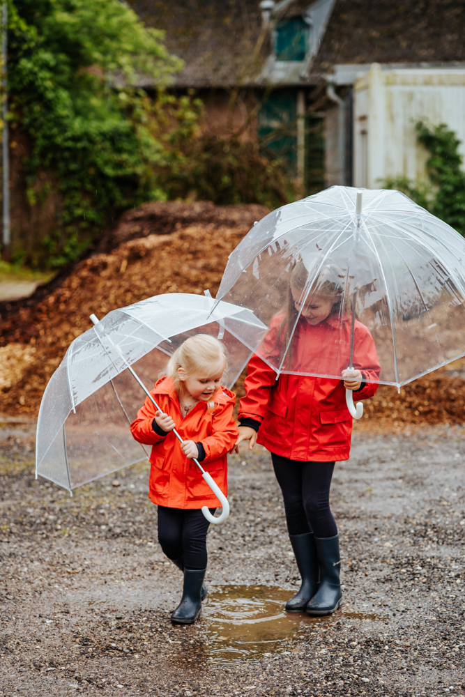 Mädchen laufen mit Regenschirm durch Regen