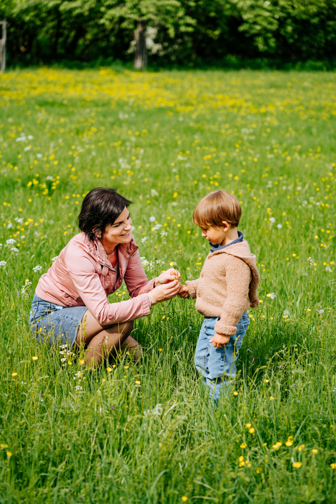 Mutter reicht Sohn Blume auf Blumenwiese